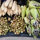 Huitlacoche-infected corn cobs for sale alongside tomatillos and corn husks.