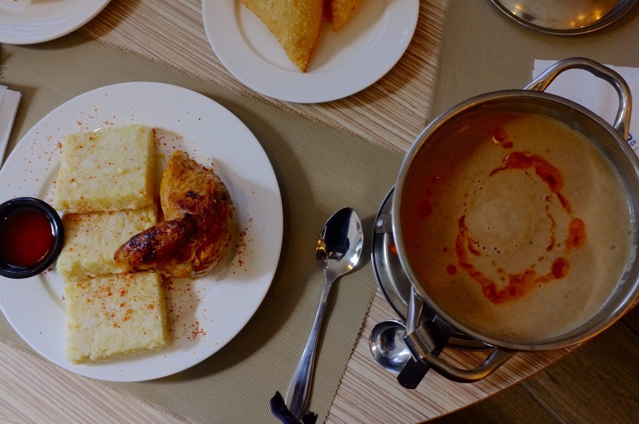 A plate of bulgur-and-rice patties with chicken sits alongside a bowl of rich, spicy gravy.