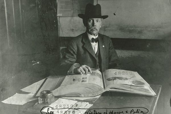 Sam Howe with one of his crime-clippings scrapbooks at police headquarters in city hall, 1908.