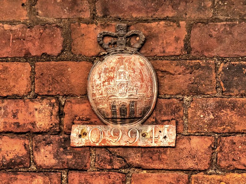 A dashing English fire mark still attached to its building.