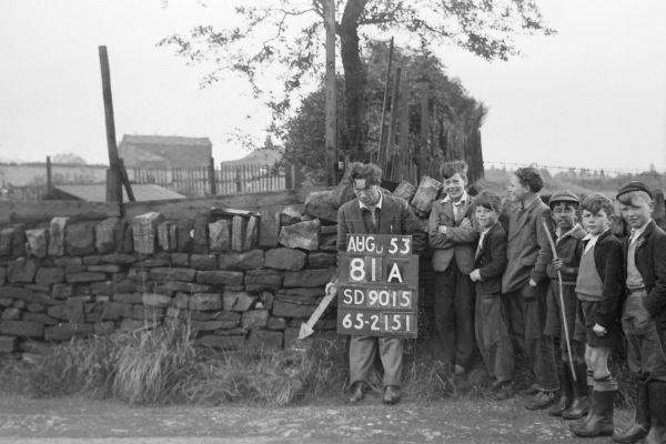 An Ordnance Survey worker points his arrow at a revision point, while laughing children look on. 