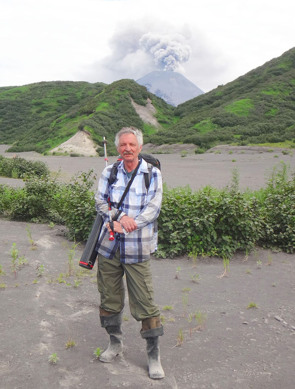 Yuri Taran shown with the volcano Karymsky erupting in Kamchatka.