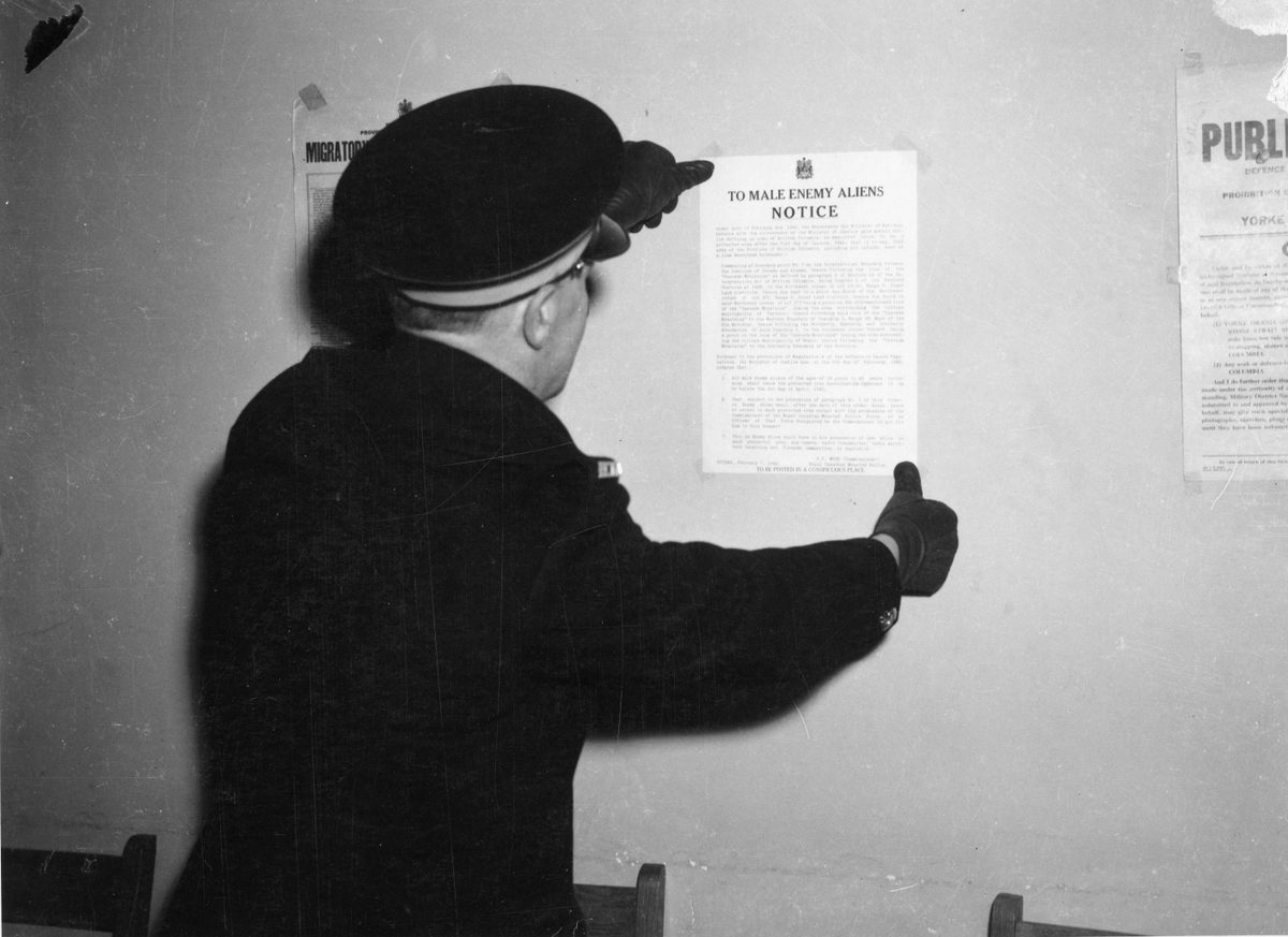 An officer posts a notice in 1942 prohibiting male Japanese Canadians aged 19 to 45 from entering a “protected area” within 100 miles of the coast, except by special permission of the government.