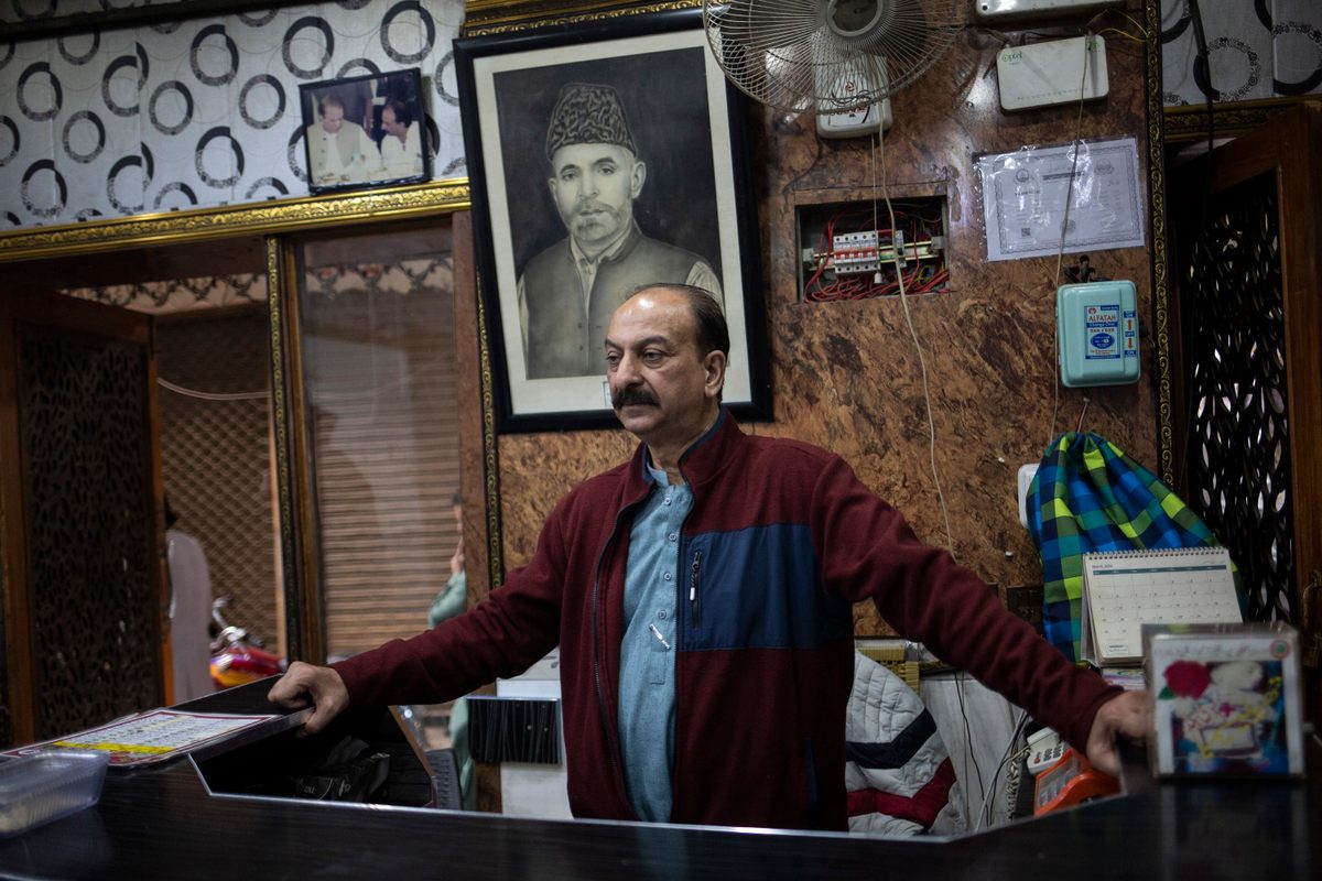 Malik Aslam stands in front of a photograph of his father, who started the Dilbar Hotel in 1950.
