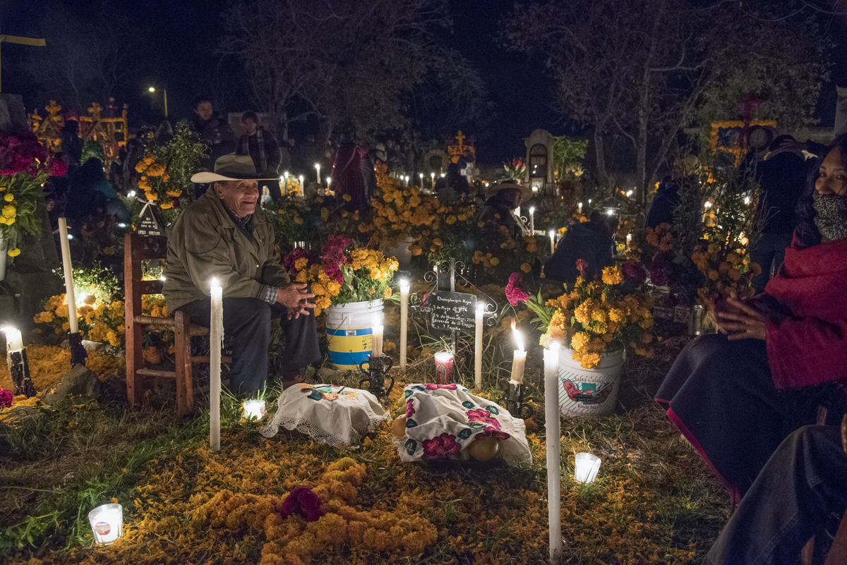 An abuelo tells a story in a graveyard in Michoacán.
