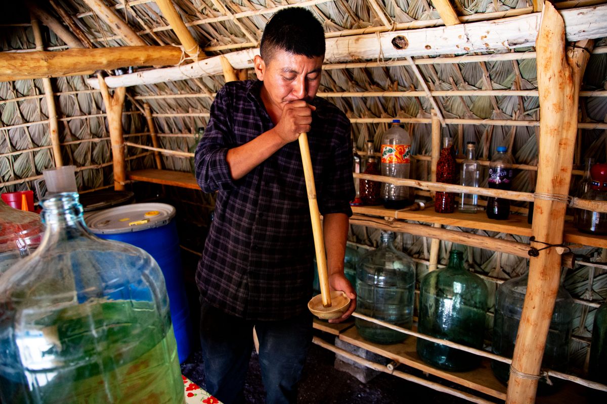 To make <em>perlas</em>, Salas sucks the mezcal through a straw.