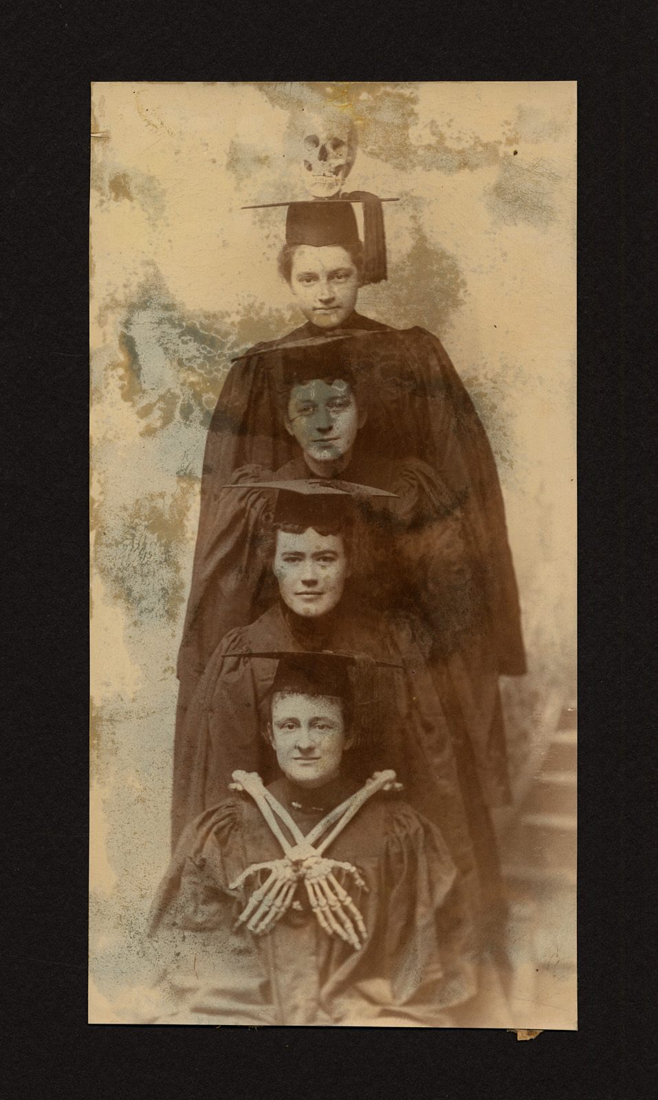 Four graduates, along with a skull and some bones, from the scrapbook of Laura Heath Hills, class of 1896.