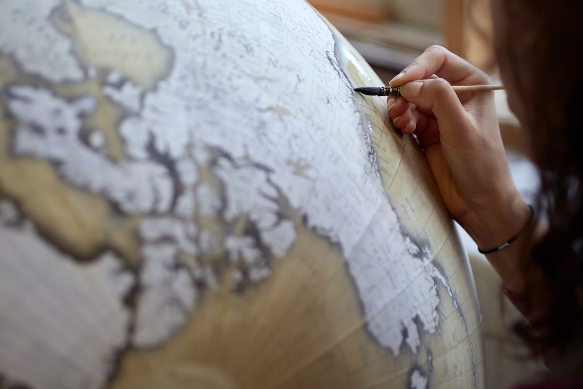 Watercolour artist Isis who has been with the company over 3 years paints the detail on the larger globes, here she is shading around the continents on an 80cm globe. Photo by Tom Bunning.