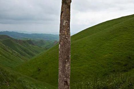 Lush green hills in the background of a phallic headstone
