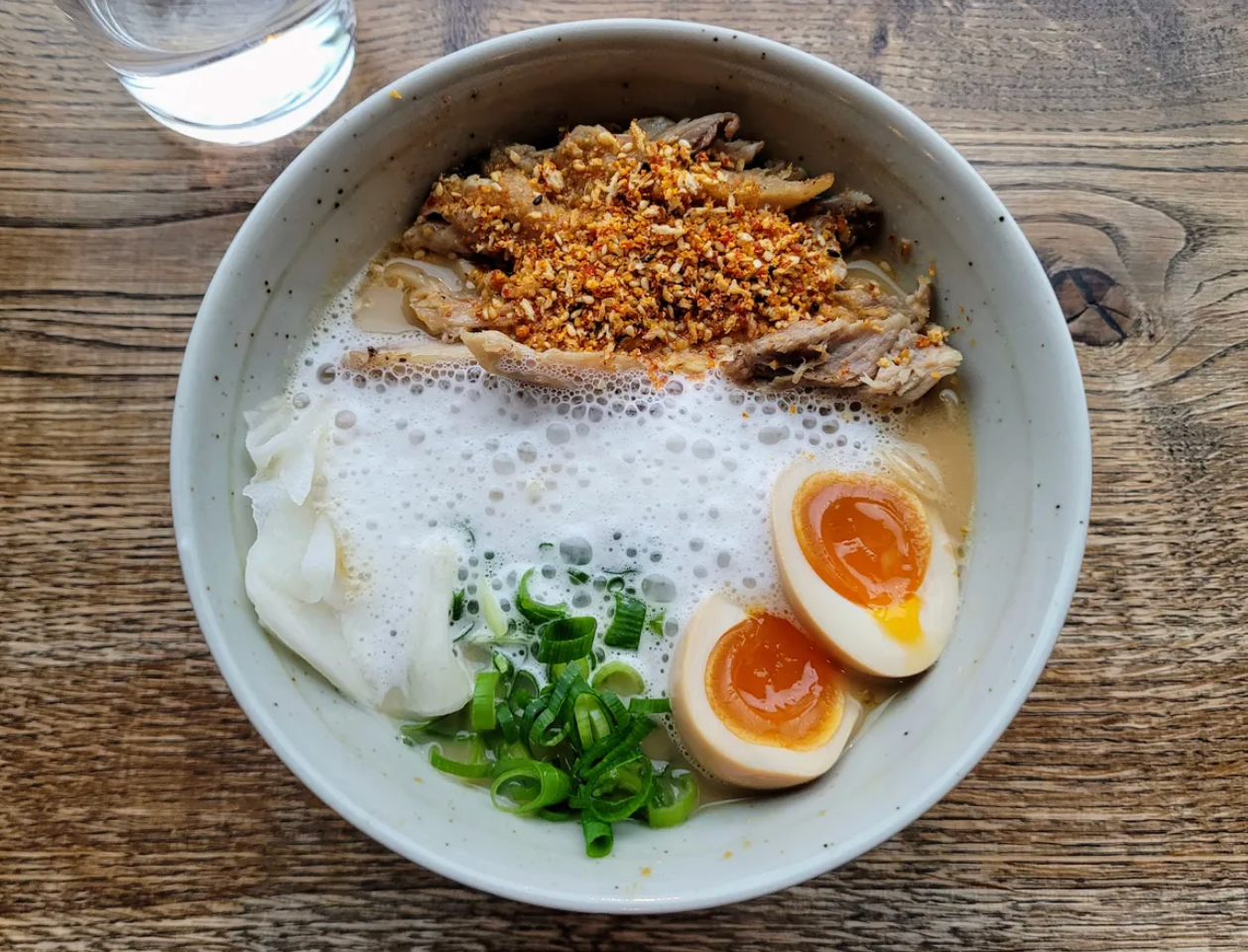 Shoyu paitan soup with koji confit chicken, black garlic fat, pickled daikon, chasu egg, and spring onion.