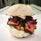 A blaa bread sandwich with steak, onion, mushroom, scallion and horseradish mayo.