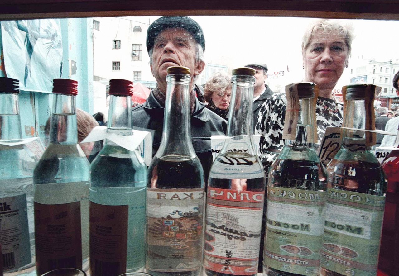 A crowd looks at different kinds of vodka for sale in a Moscow street kiosk.
