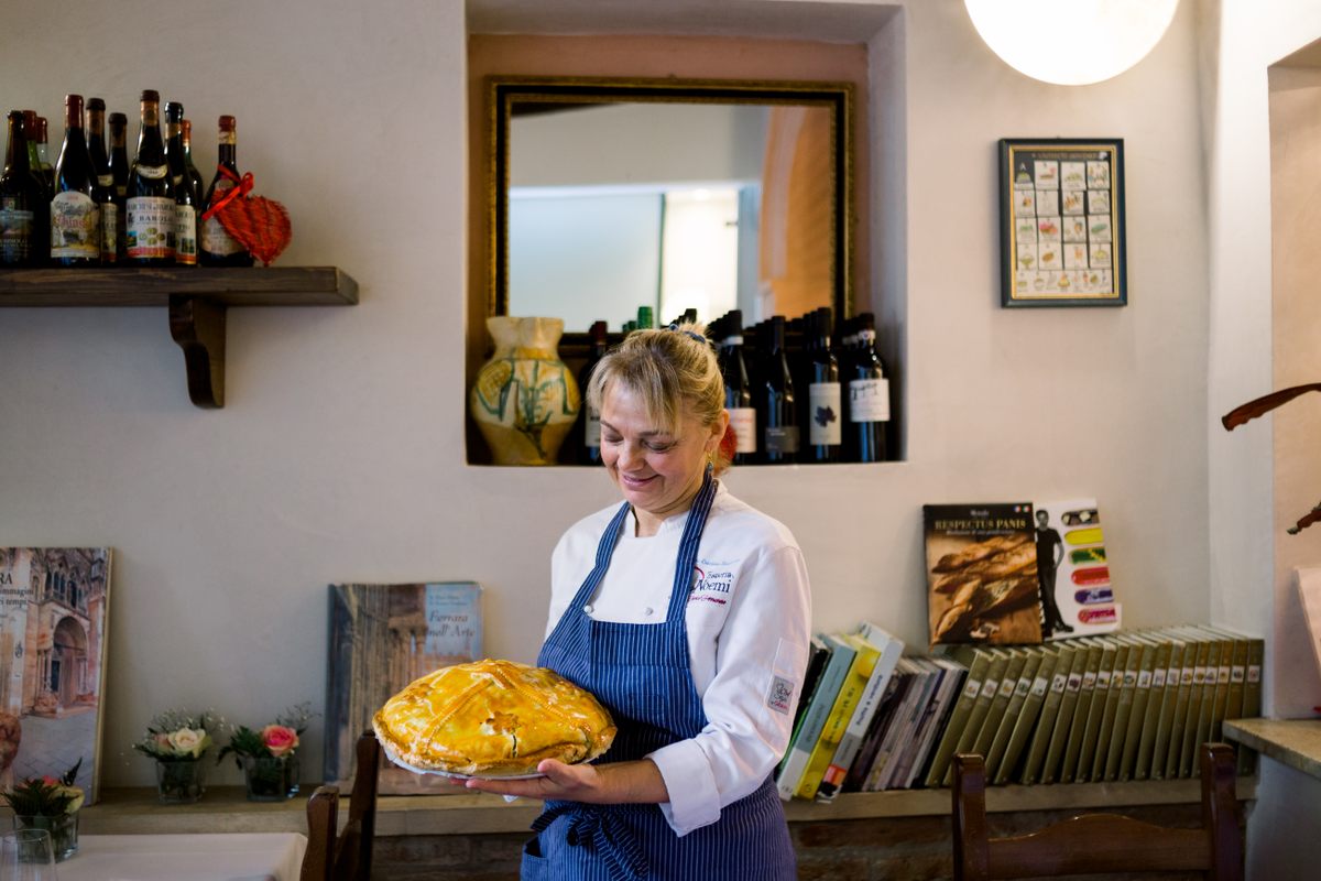 Maria Cristina Borgazzi, the daughter of Noemi, who opened the eponymous trattoria in 1958, holding one of the restaurant's main dishes: pasticcio.