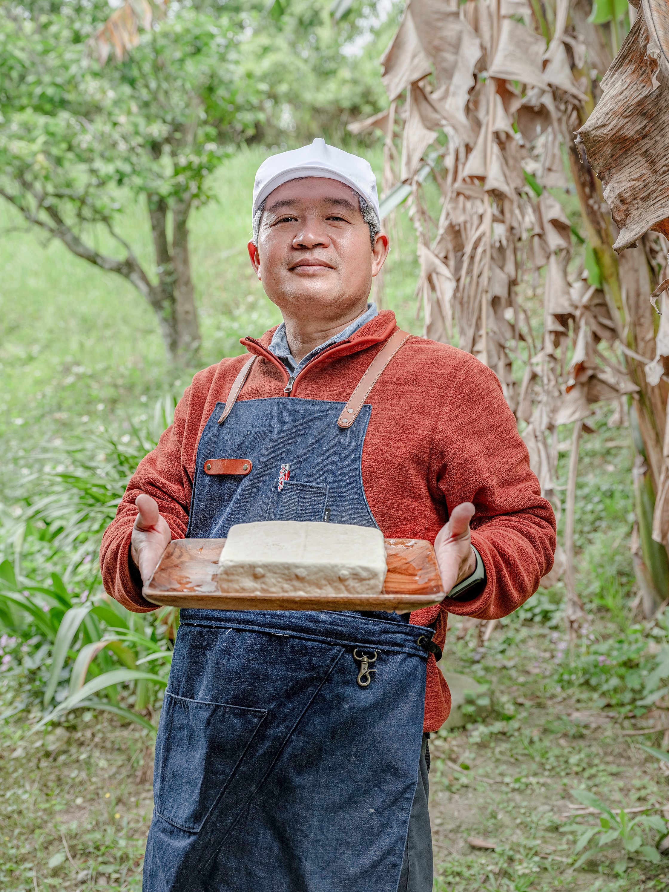 Lin Yih-Cheng holds the volcanic tofu in their garden.