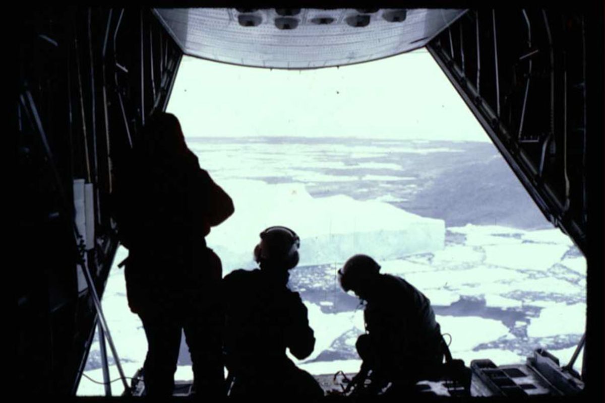 Members of the International Ice Patrol monitor a tabular iceberg from a C-130 plane.