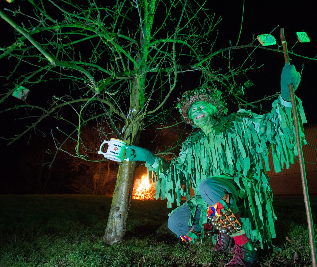 A Green Man enjoying some cider and a fire.