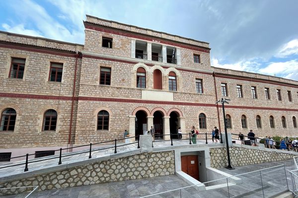 A large stone 3 and 2-story building with arched windows