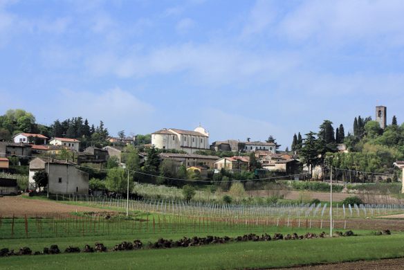 A rural Italy town with a farm in front and blue skies overhead