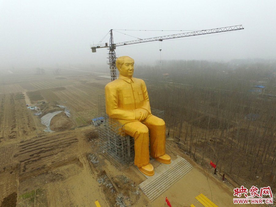 A crane and some scaffolding, also looking pretty small next to the huge Mao.