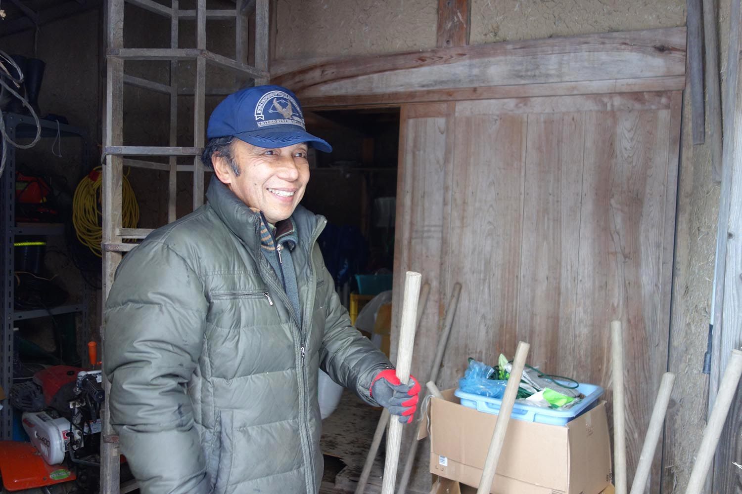 Nimaida with tools for rice farming: the latticed tower behind him will be laid down and rolled along the soil to mark a grid for planting.