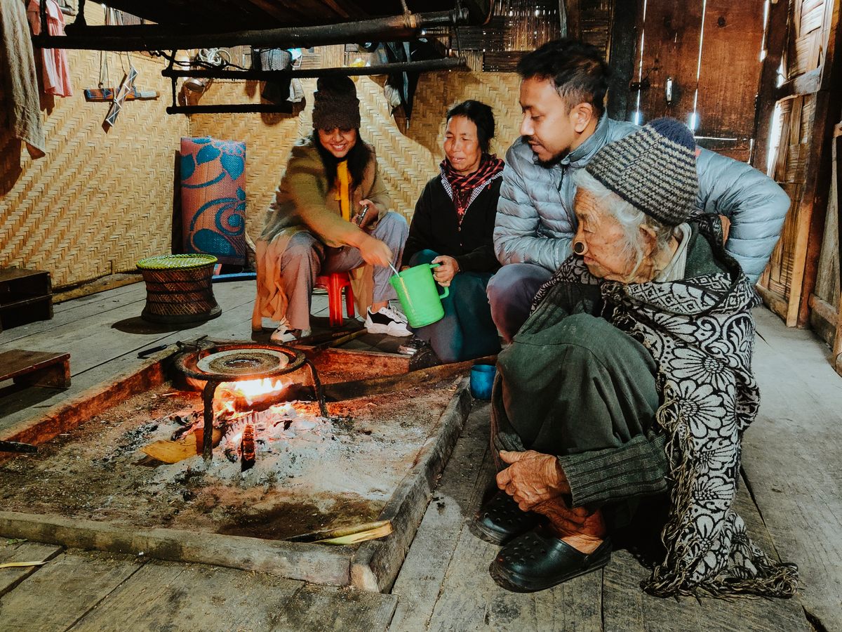 An Apatani family and guests make tapyo around the hearth.