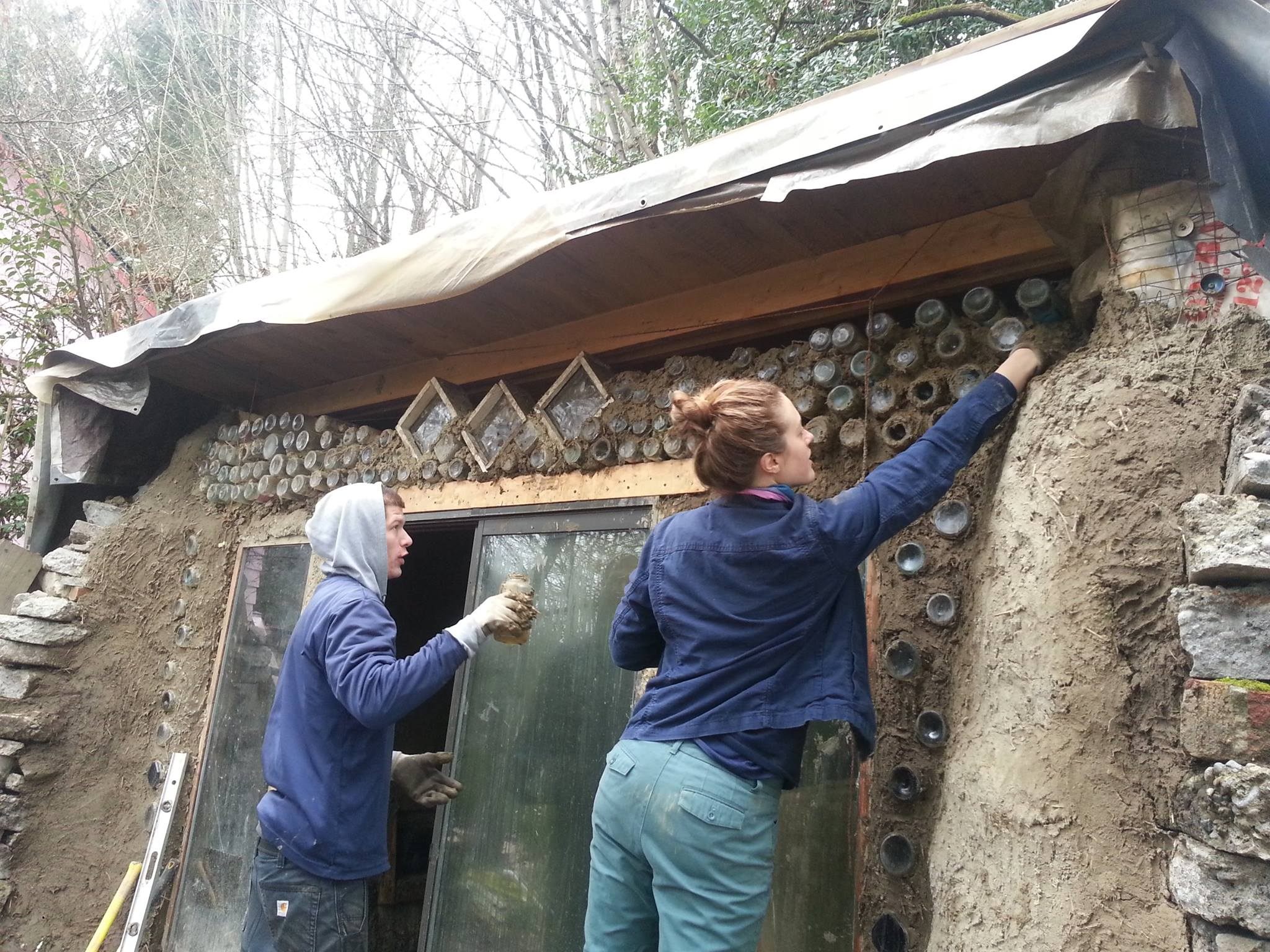 Volunteers at the Trash Studio arrange glass bottles on the facade of the building.