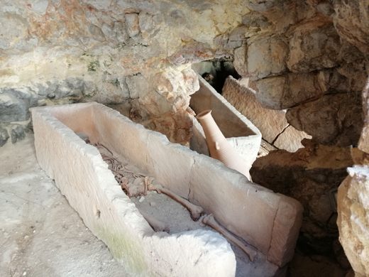A damaged sarcophagus sits in a stone-walled burial chamber