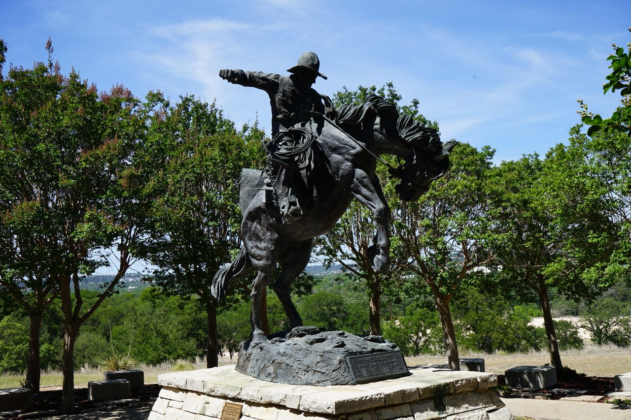 A sculpted cowboy rides a bucking horse in the garden of the Museum of Western Art.