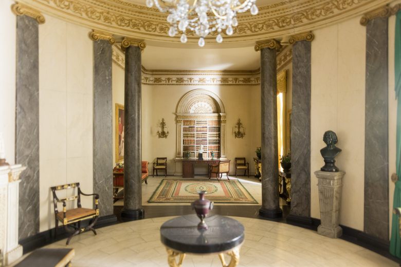 A miniature Neoclassical library with marble columns, a crystal chandelier, and a built-in arched bookcase.