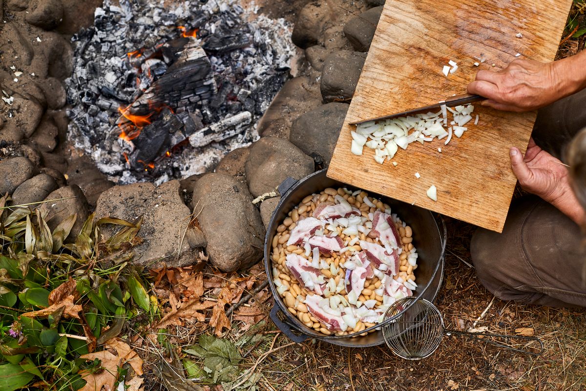 Layer the beans in the kettle with salt pork, onions, and a mixture of broth, salt, pepper, and molasses.