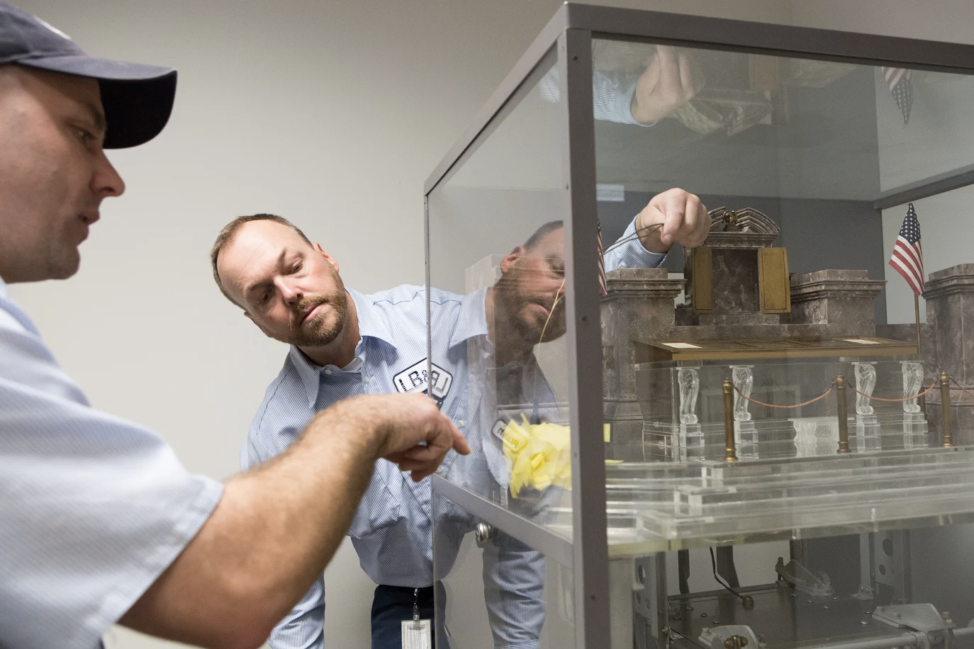 National Archives staff carefully dust the vault model.