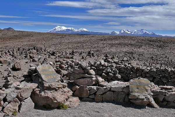 Mountain peaks rise from the horizon above Apachetas in the foreground 
