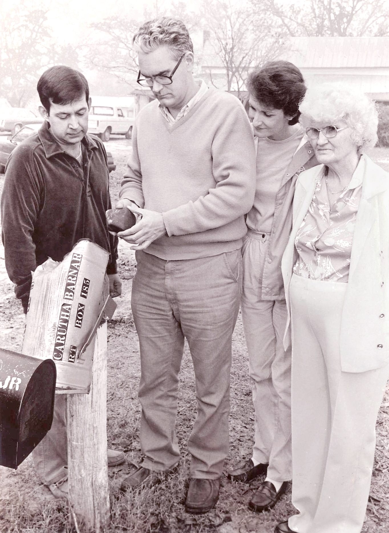 This staged photograph shows meteorite collector Hal Povenmire (second from left) inspecting the meteorite that impacted Carutha Barnard's (far right) mailbox in Georgia on December 10, 1984. Povenmire eventually purchased the meteorite and the mailbox from Barnard.