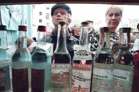 A crowd looks at different kinds of vodka for sale in a Moscow street kiosk.