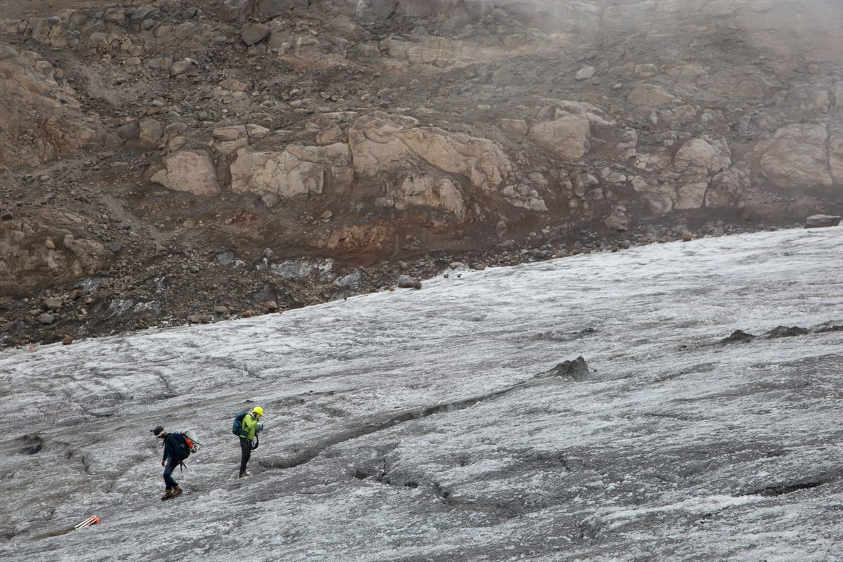 Ceballos and Mendoza hike up Santa Isabel glacier, blackened by ash fall from Ruiz volcano.