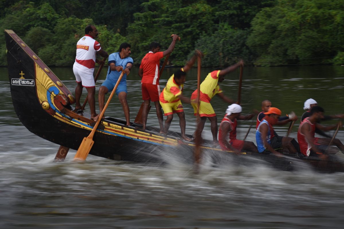 Jiffy Felix, in light blue, captains around 100 rowers from the back of his team's snake boat.