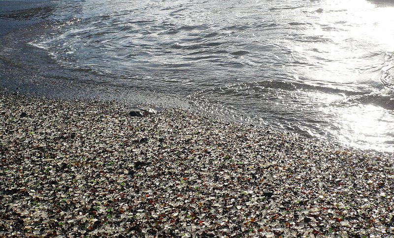 The waves wash over the mix of rocks and ground-down glass pieces on the site of a former trash dump, now Glass Beach in Fort Bragg, California