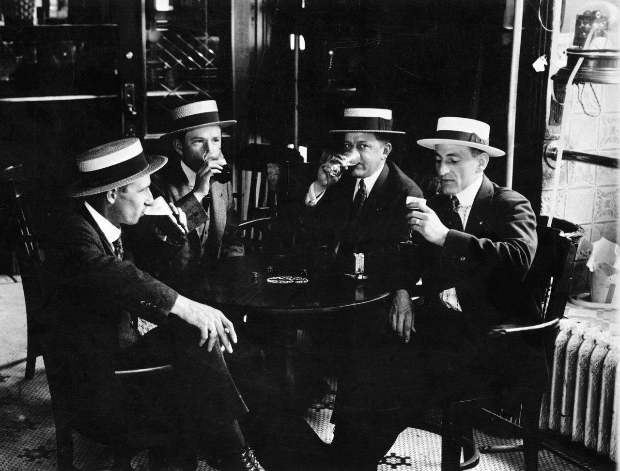 Four men in boater hats enjoy a last drink together before Prohibition begins in 1919.