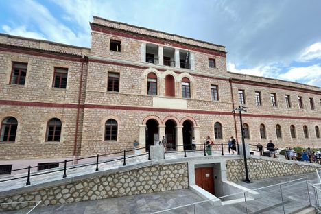 A large stone 3 and 2-story building with arched windows