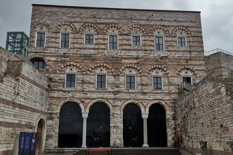 A three story outer wall with arches on the first floor and alternating white and red stonework.