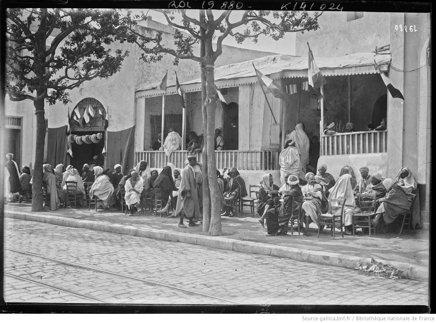 French flags are visible above Tunisians at this early-20th century cafe.