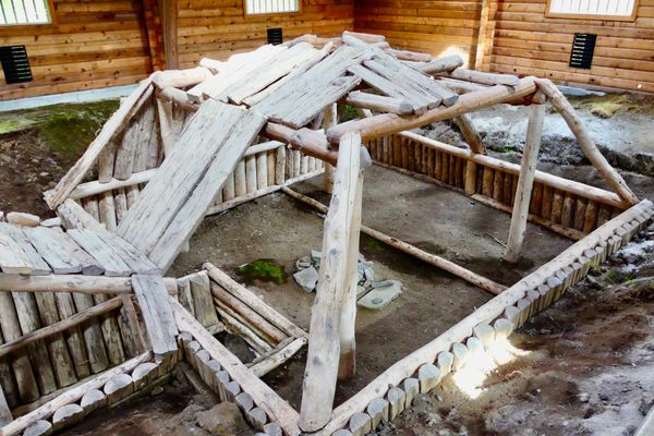 A partial reconstruction of a 700-year-old pit house, where it originally stood, on the ancient bank of the Brooks River. A modern hut has been built around it to preserve the site.