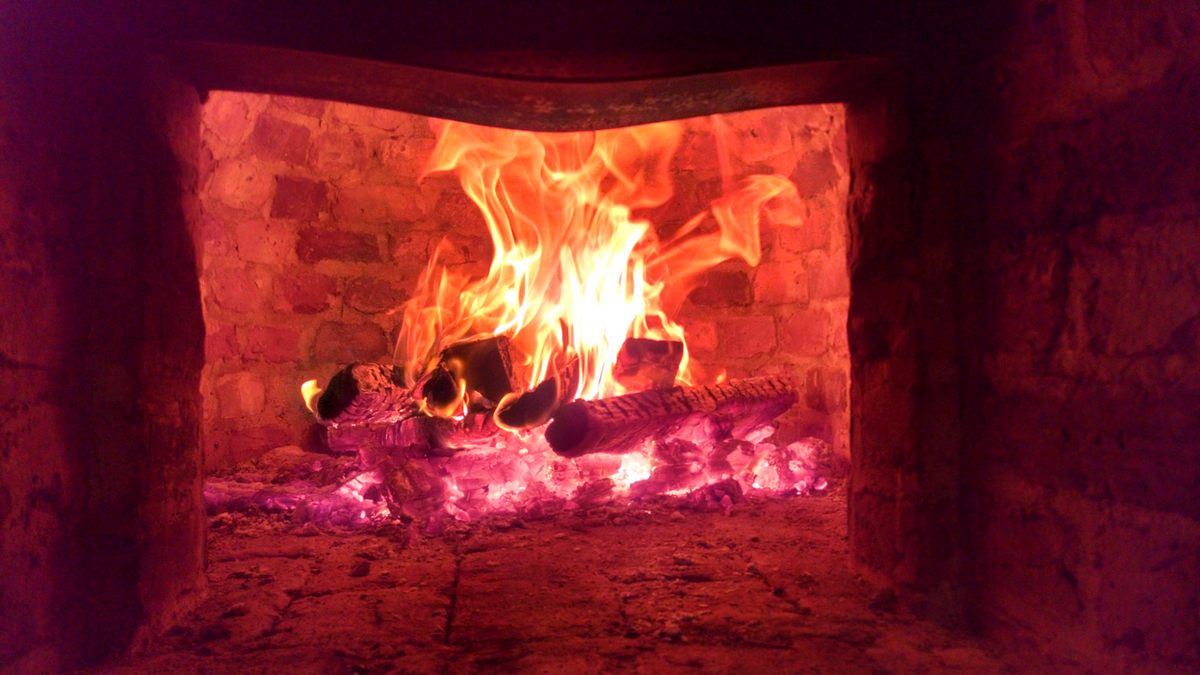 The interior of a historical oven, which opens into a large, fiery dome from a narrow door.