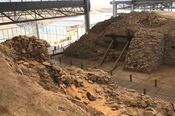 An ancient wall with a path running through it under a metal roof