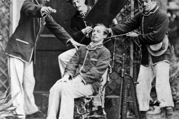 A Victorian-era sitter is clamped into position using a metal frame before having his portrait taken. 