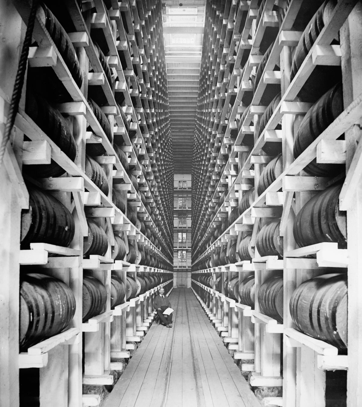Worker Sitting in Rack Warehouse, Hiram Walker & Sons, Walkerville, Ontario, Canada, circa 1910.