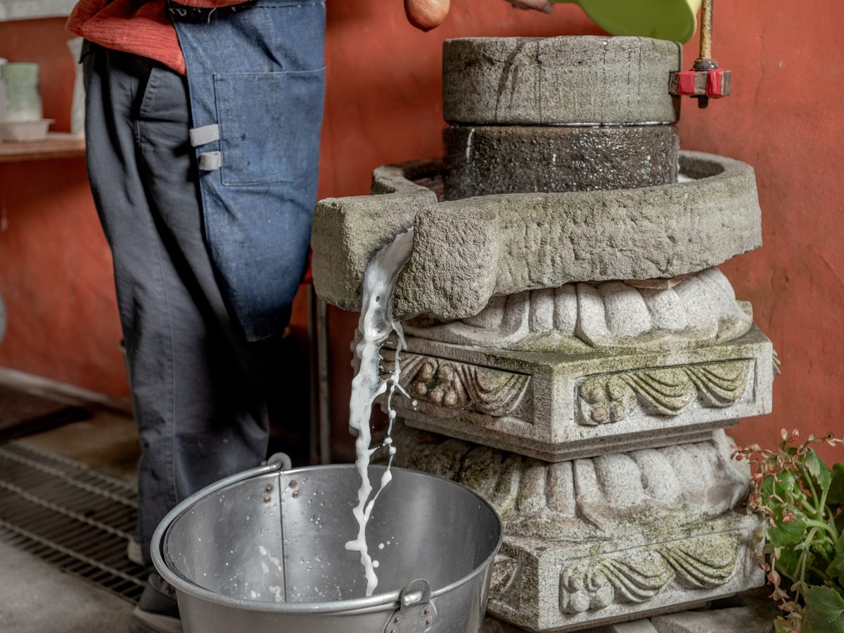 Soy milk pours from the stone mill.