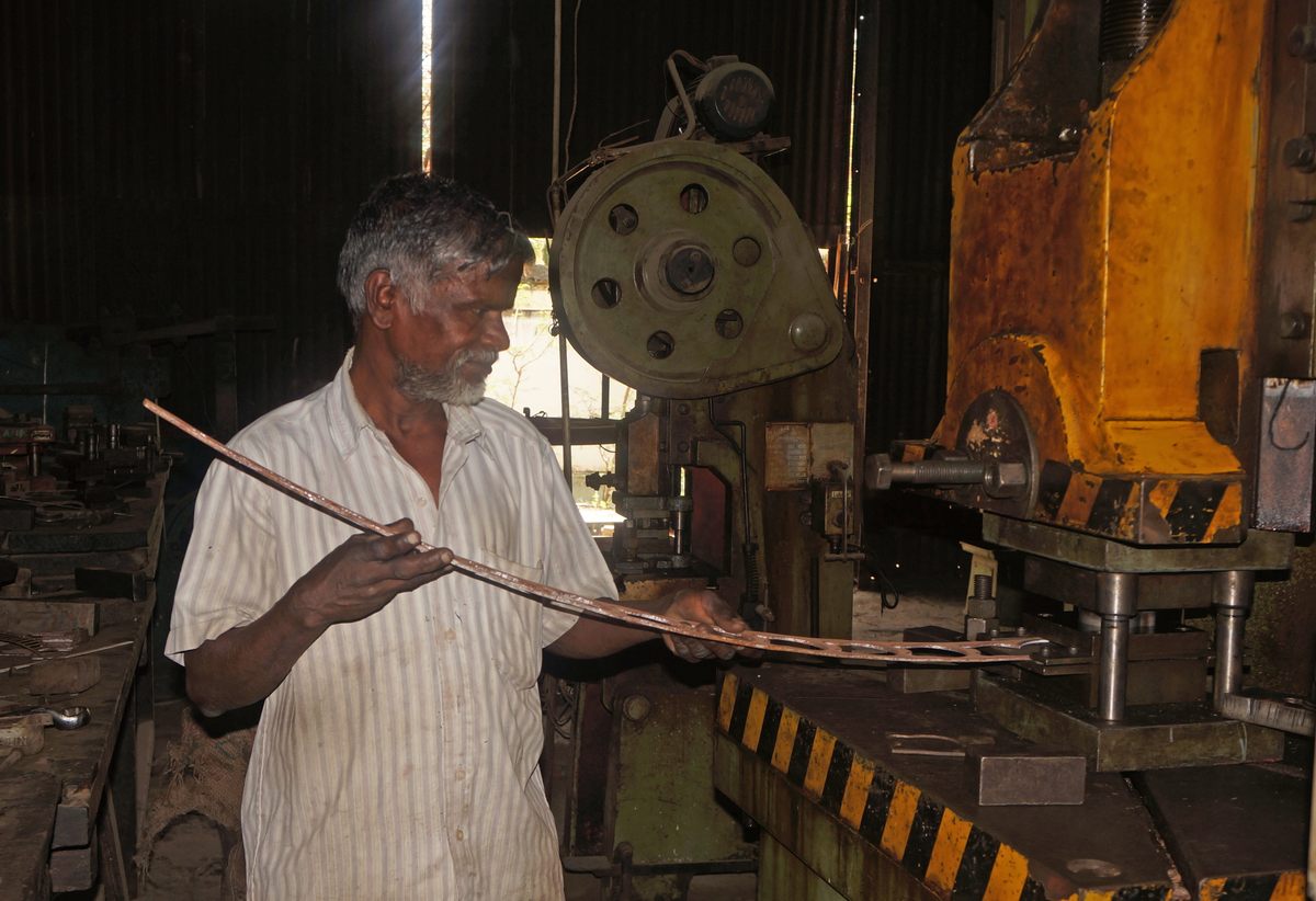 C. Murugesan, a 30-year veteran of the industry, demonstrates how the outer iron casing of a mango lock is cut using molds shaped like mangoes.