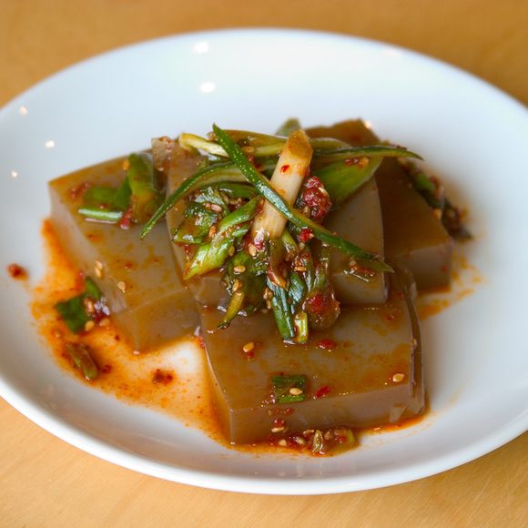 Acorn jelly is often seasoned with soy sauce and sesame oil, and comes topped with green onions, sesame seeds, and Korean chili flakes (gochugaru).