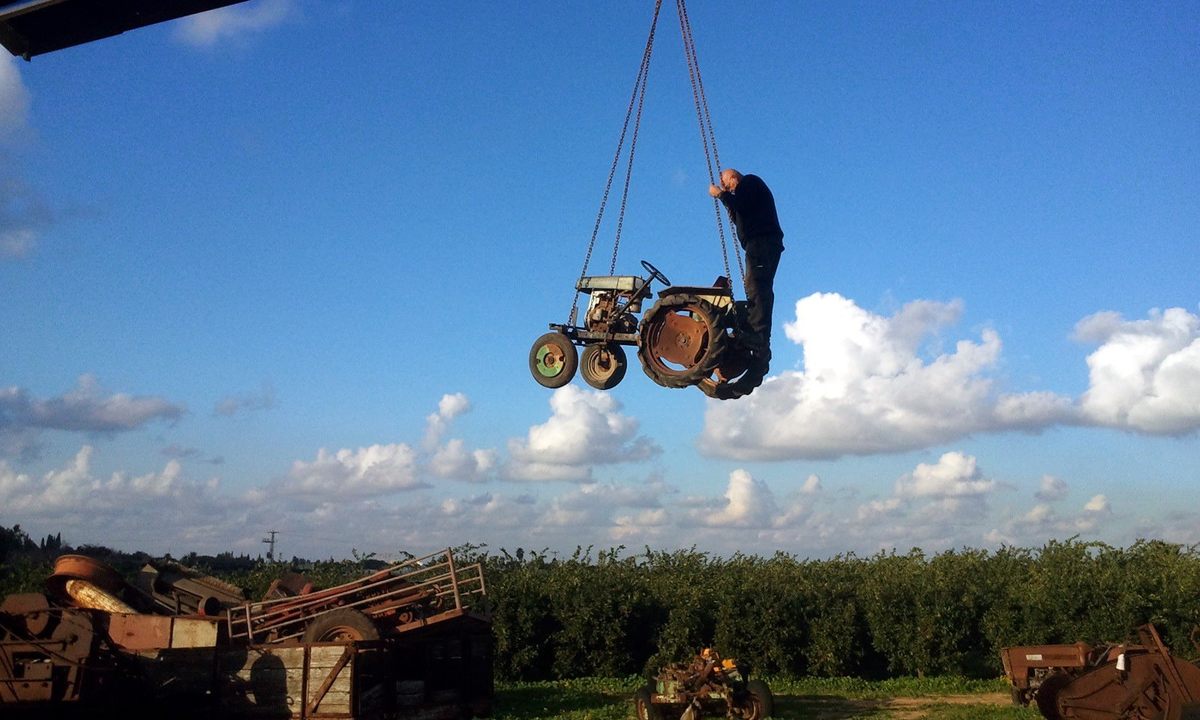 Volunteers use a crane to transport an antique tractor to the museum.
